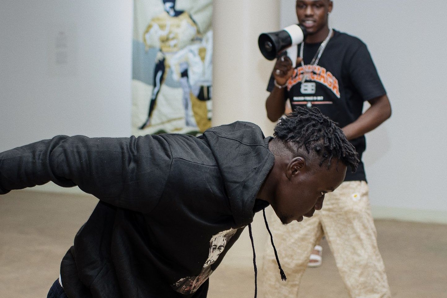 Performance dansée dans la galerie devant une œuvre textile, un participant au mégaphone